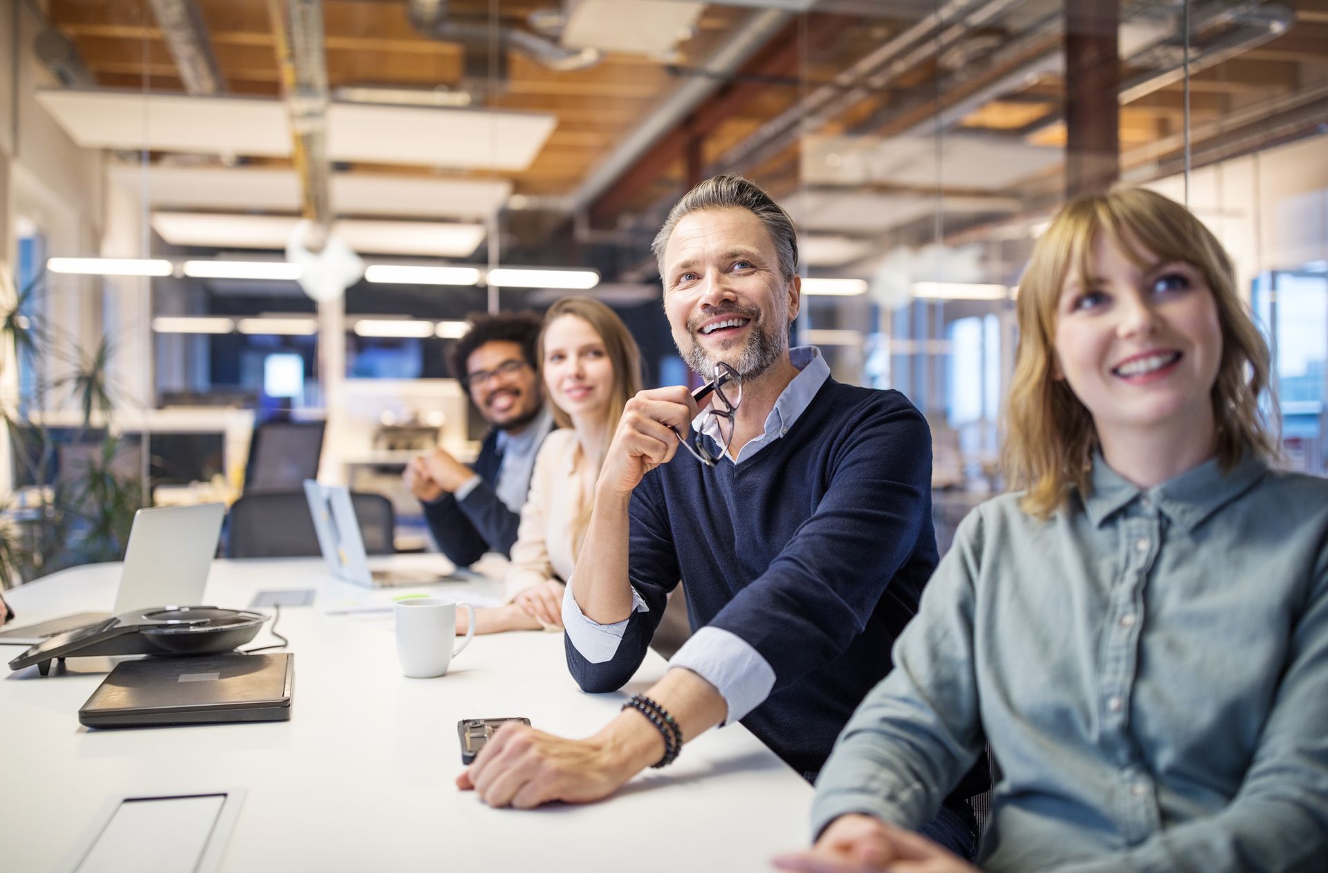 Gruppe von Mitarbeiter:innen in einem Büro sitzend, die gemeinsam an einer modernen Kommunikationslösung arbeiten.