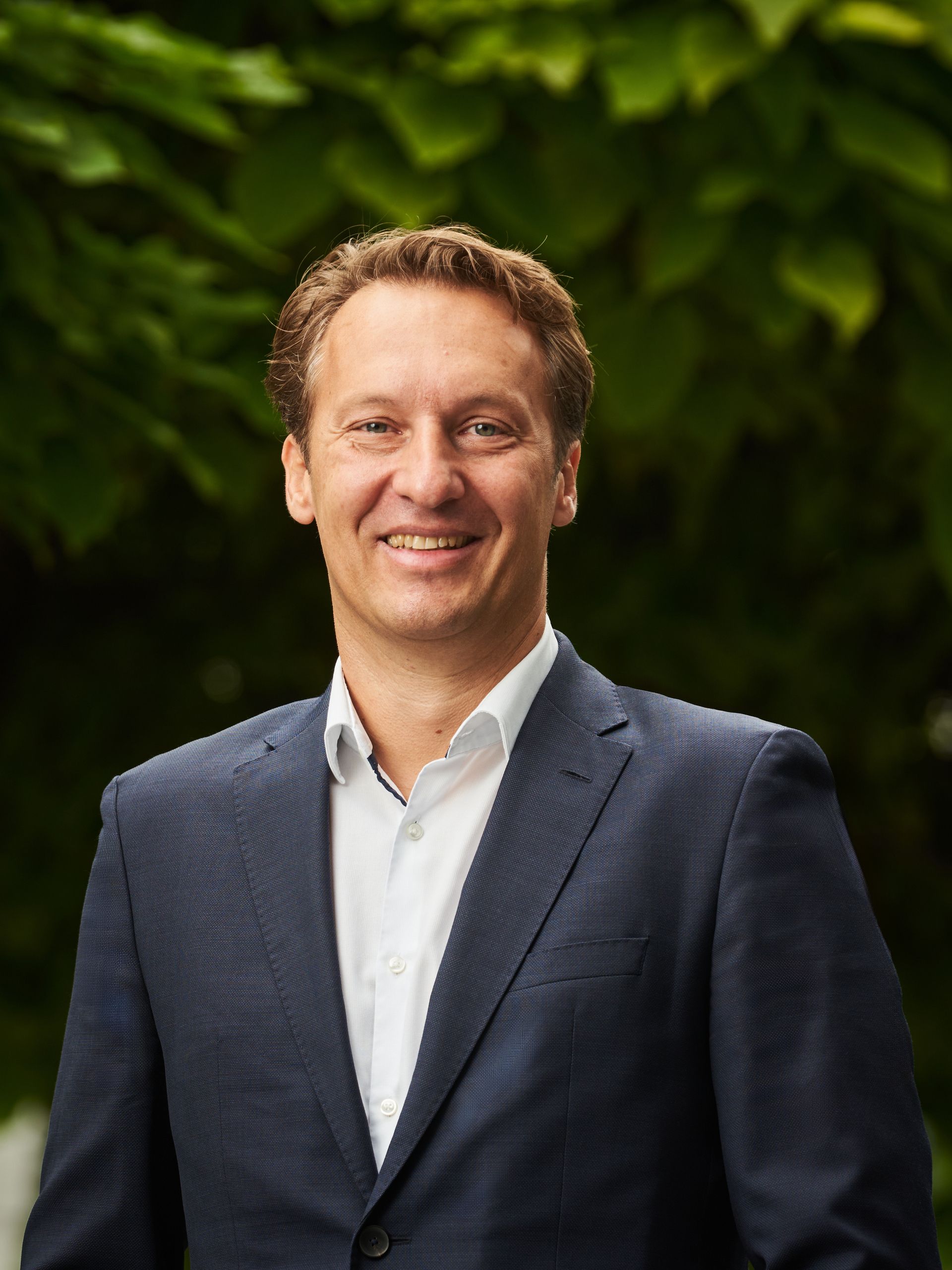 Ein Mann in einem Anzug lächelt in die Kamera, passend zur Presseinfo-Seite von CANCOM Austria.